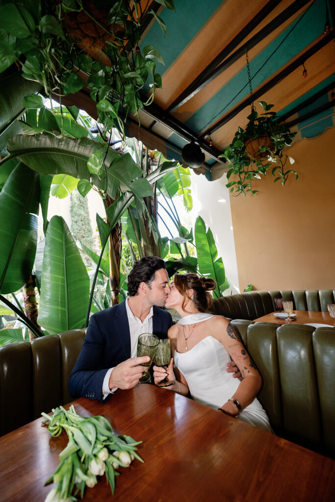 Bride and groom kissing while surrounded by tropical greenery at Habana in Irvine Spectrum after elopement.