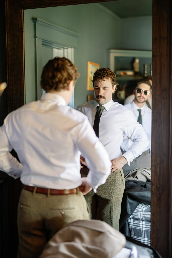 Groom getting ready in the mirror during his Swanner House wedding. 