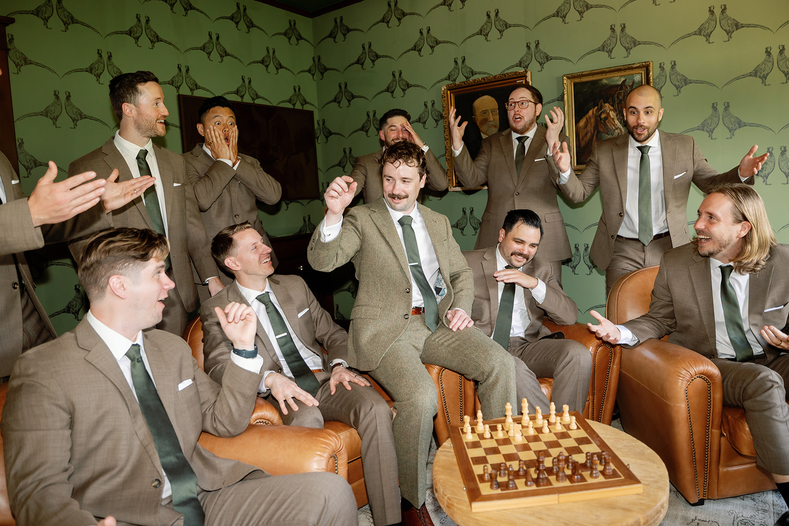 Groomsmen reacting together in green wallpaper room during Swanner House wedding getting ready.