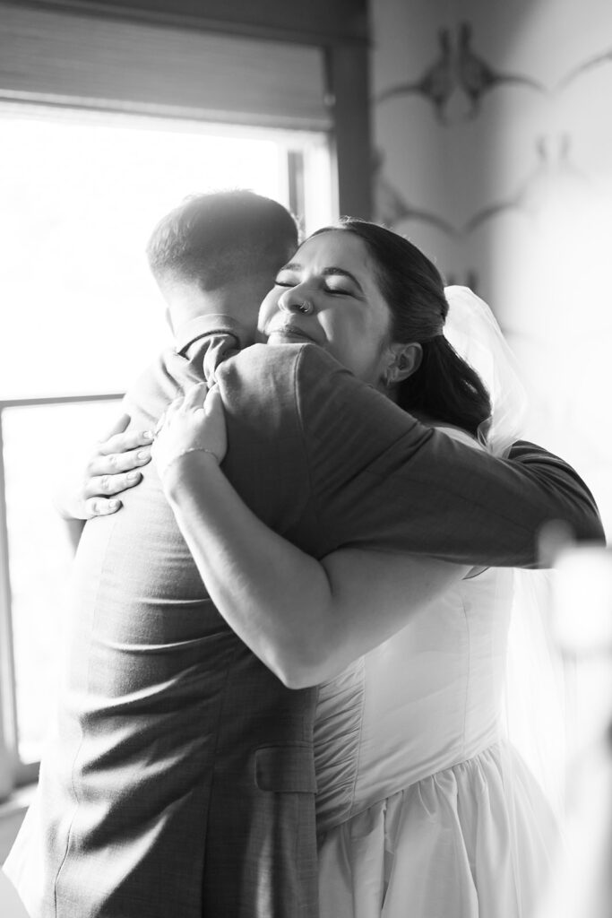 Black and white photo of the bride hugging a groomsmen at The Swanner House in San Juan Capistrano.
