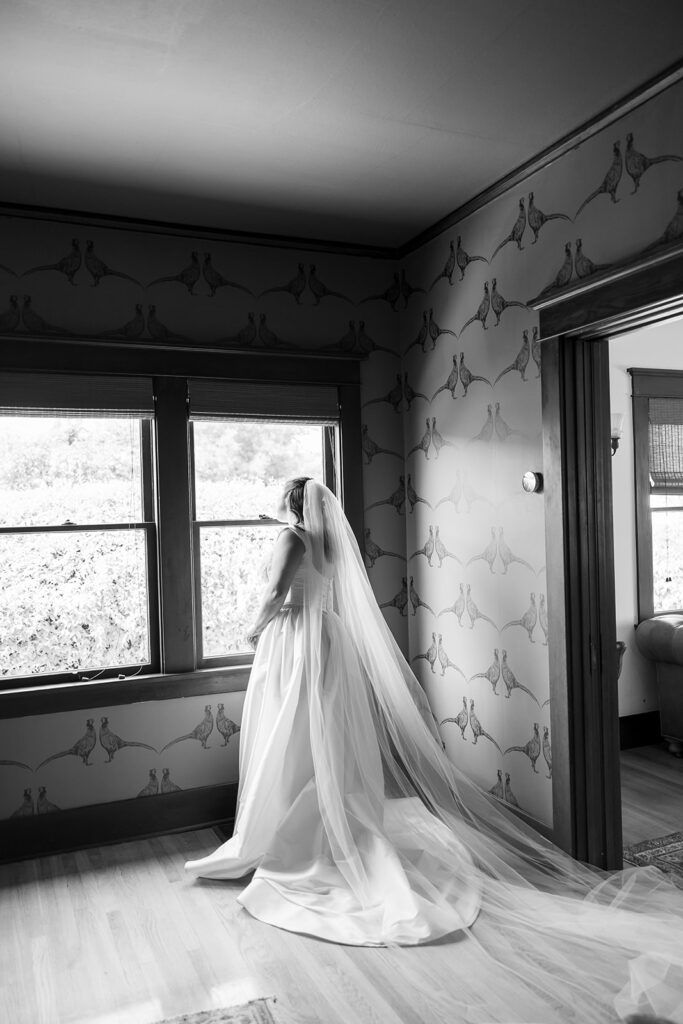 Black and white portrait of a bride standing by window with veil during getting ready at Swanner House wedding.