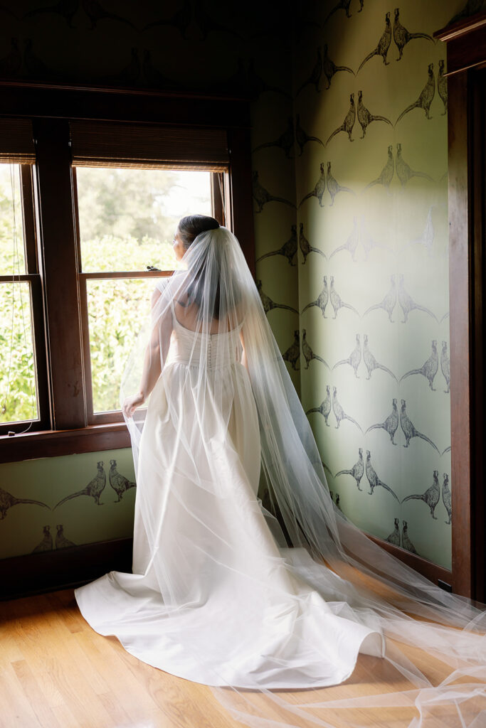 Bride standing by window with veil during getting ready at Swanner House wedding.