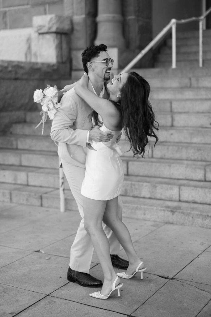 Candid photo of a bride and groom laughing together in black and white portrait outside Old Orange County Courthouse.