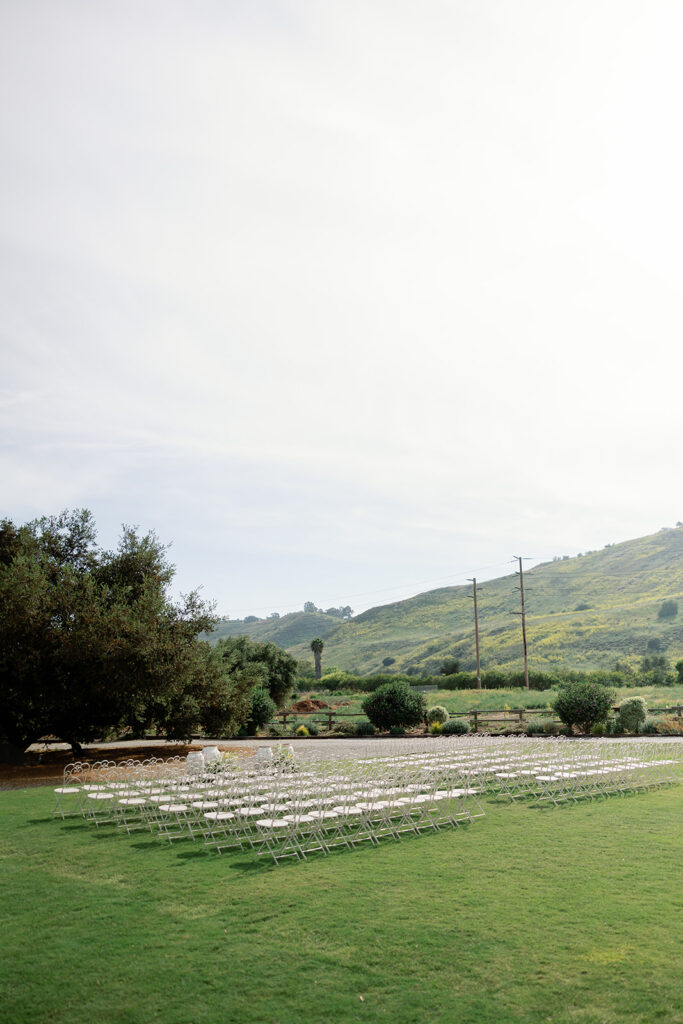 Outdoor ceremony setup with white chairs and rolling hills at Swanner House wedding.