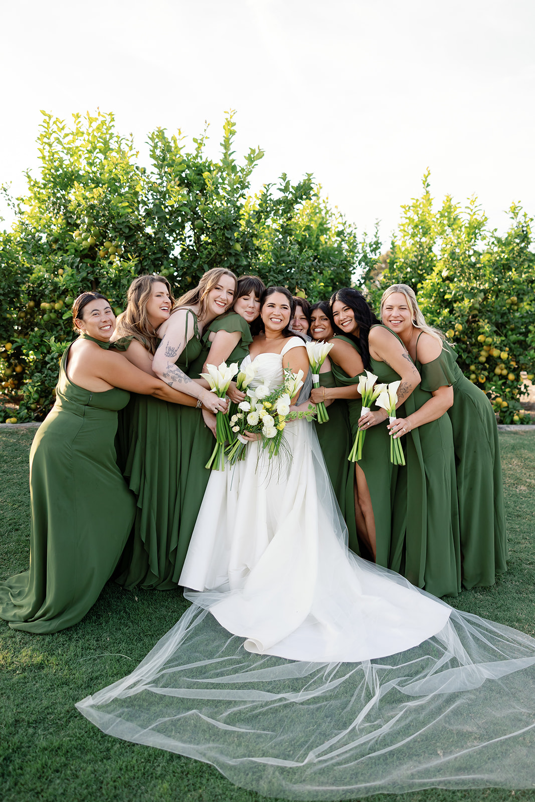 Bride with bridesmaids in green dresses posing together at Swanner House wedding in San Juan Capistrano.