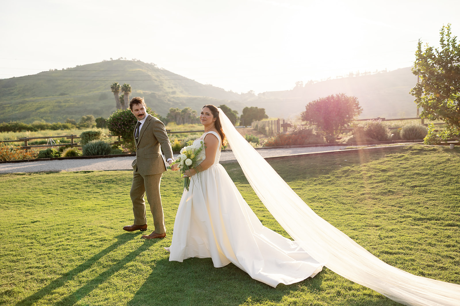 Bride and groom walking across lawn during golden hour at Swanner House wedding in San Juan Capistrano.