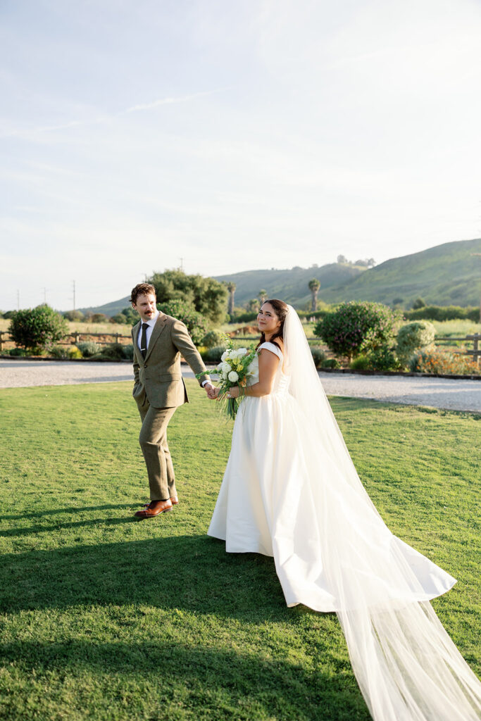 Bride and groom holding hands while walking across the lawn at The Swanner House.