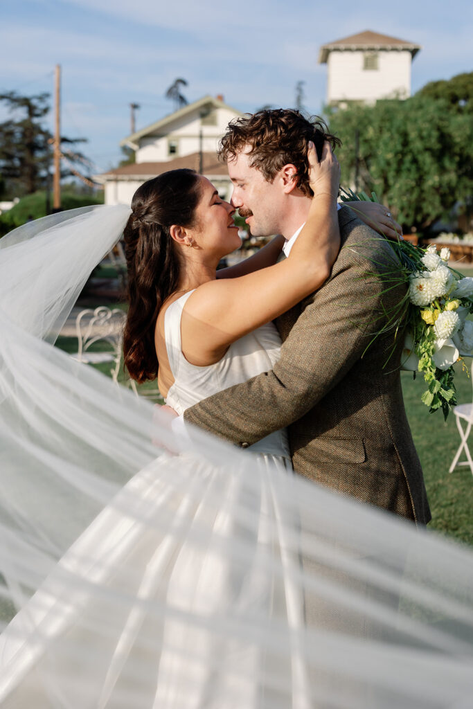 Bride and groom embracing with veil flowing at Swanner House wedding in San Juan Capistrano.
