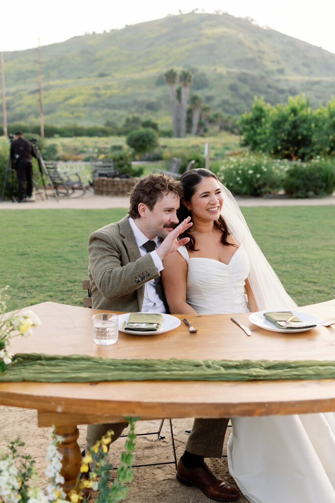 Bride and groom smiling during speeches.