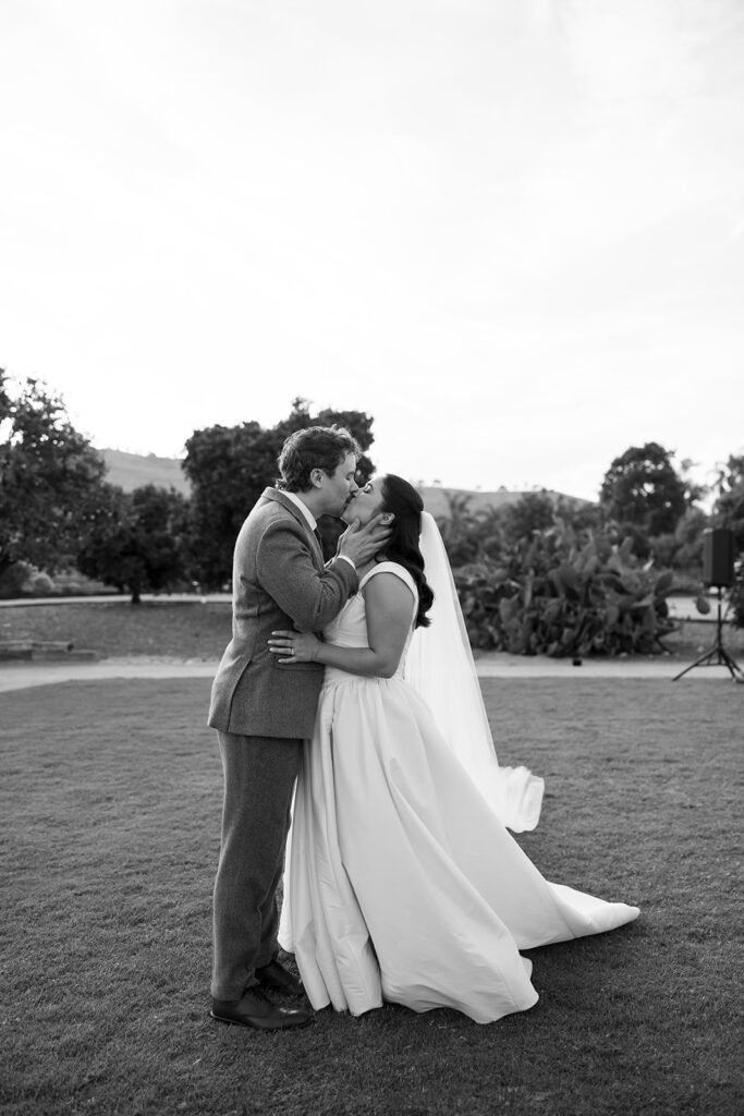 Black and white portrait of a bride and groom kissing on the grounds at The Swanner House in San Juan Capistrano.