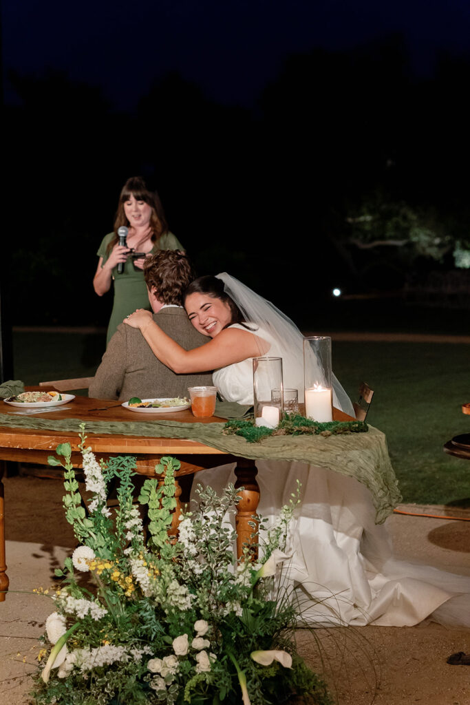 Bride hugging the groom during speeches for their Swanner House wedding reception in San Juan Capistrano.