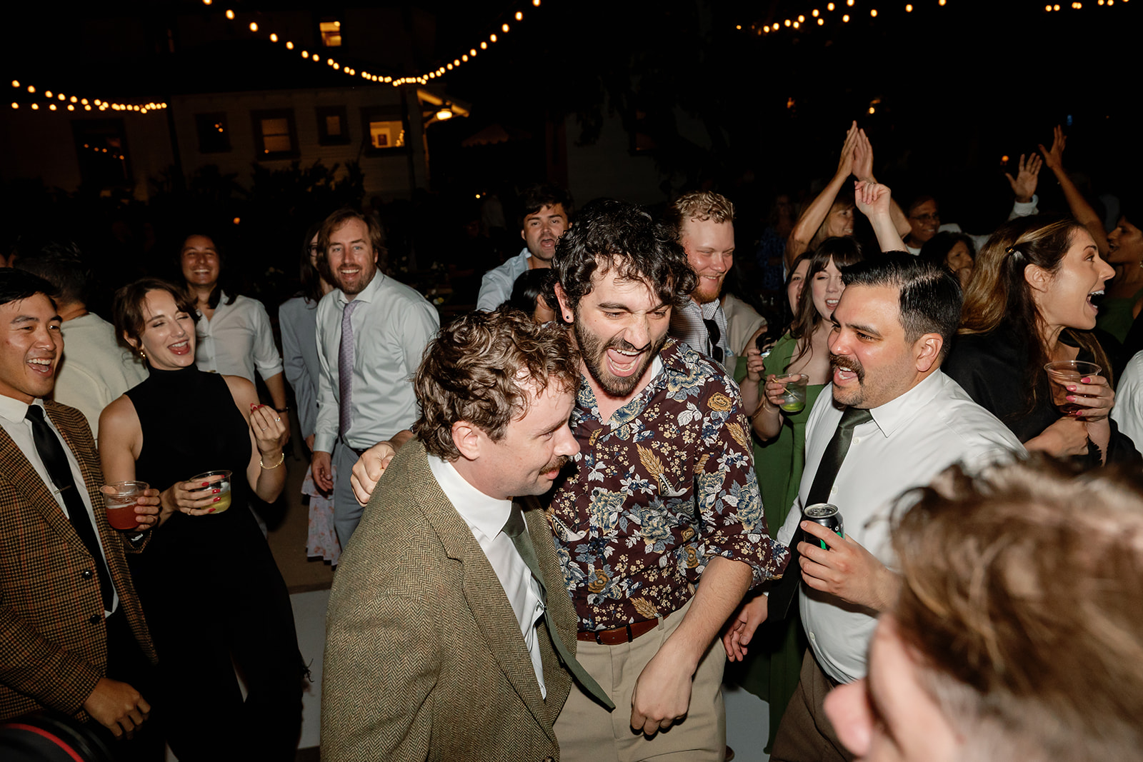Groom dancing with guests under string lights at a Swanner House wedding in San Juan Capistrano.