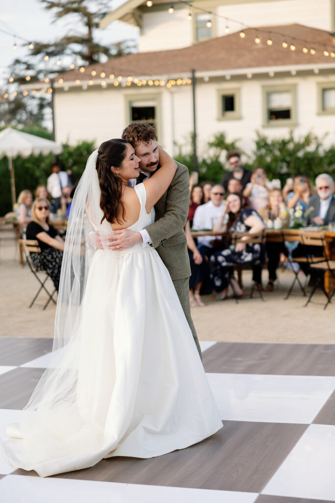 Bride and groom sharing their first dance on a checkered dance floor at a Swanner House wedding in San Juan Capistrano.