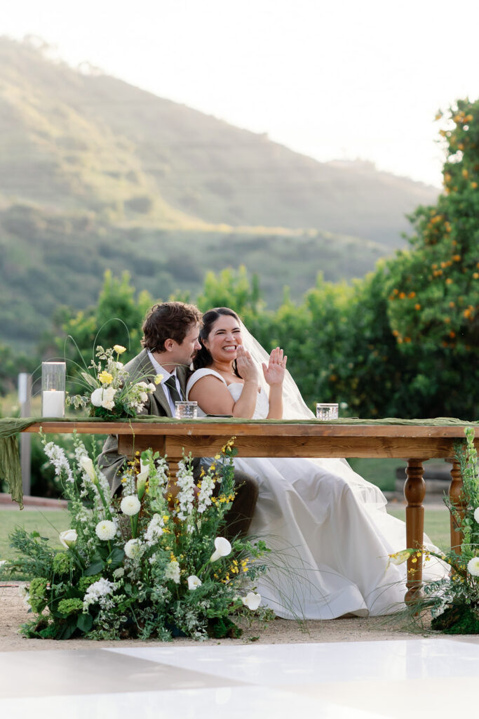 Bride and groom clapping during wedding reception speeches. 
