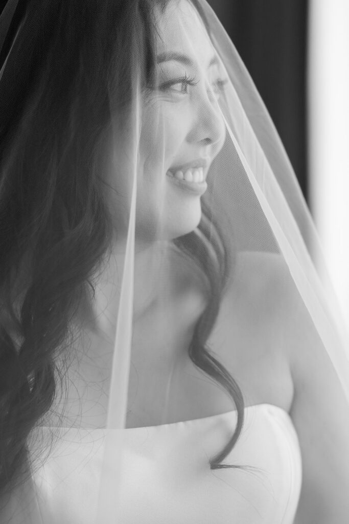 Close up indoor portrait of a bride posing underneath her veil.