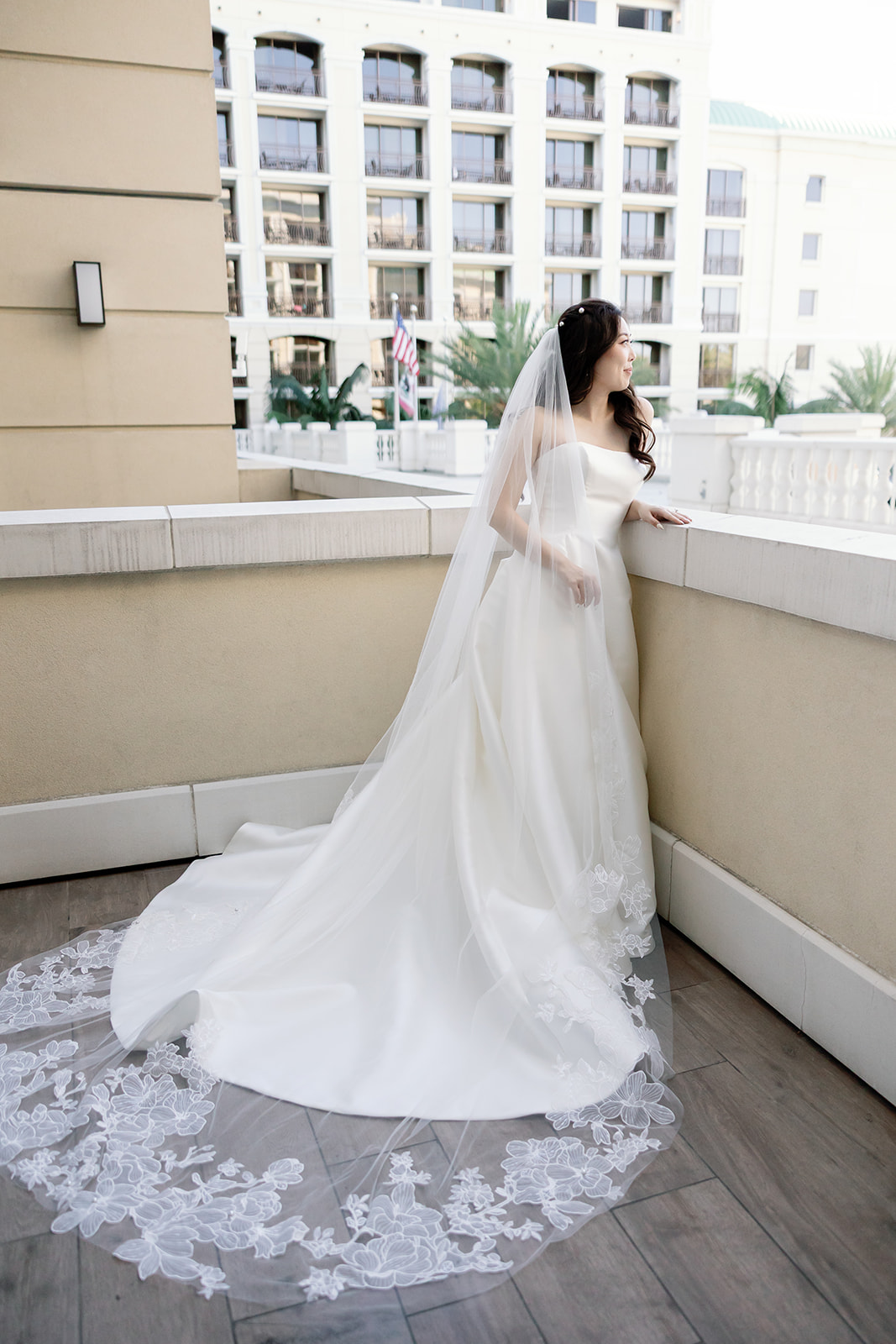 Bride posing for portraits on the balcony of her hotel room.