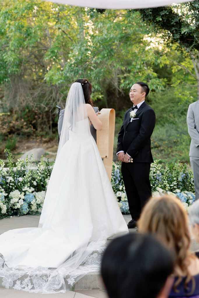 Bride readings her vows to her groom on a long scroll of paper.
