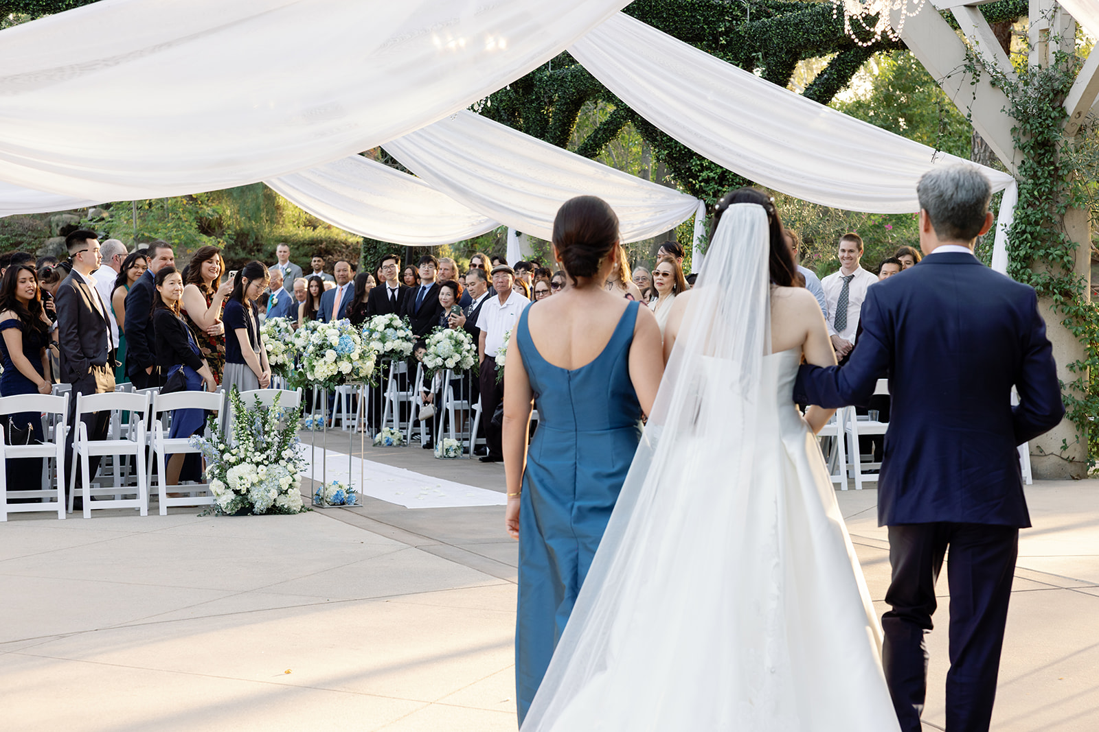 Bride being walked down the aisle by her parents for her Coyote Hills Golf Course weddind.