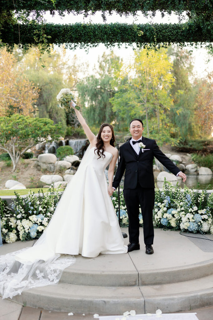 Bride and groom holding their hands out in celebration after sharing their first kiss as husband and wife.