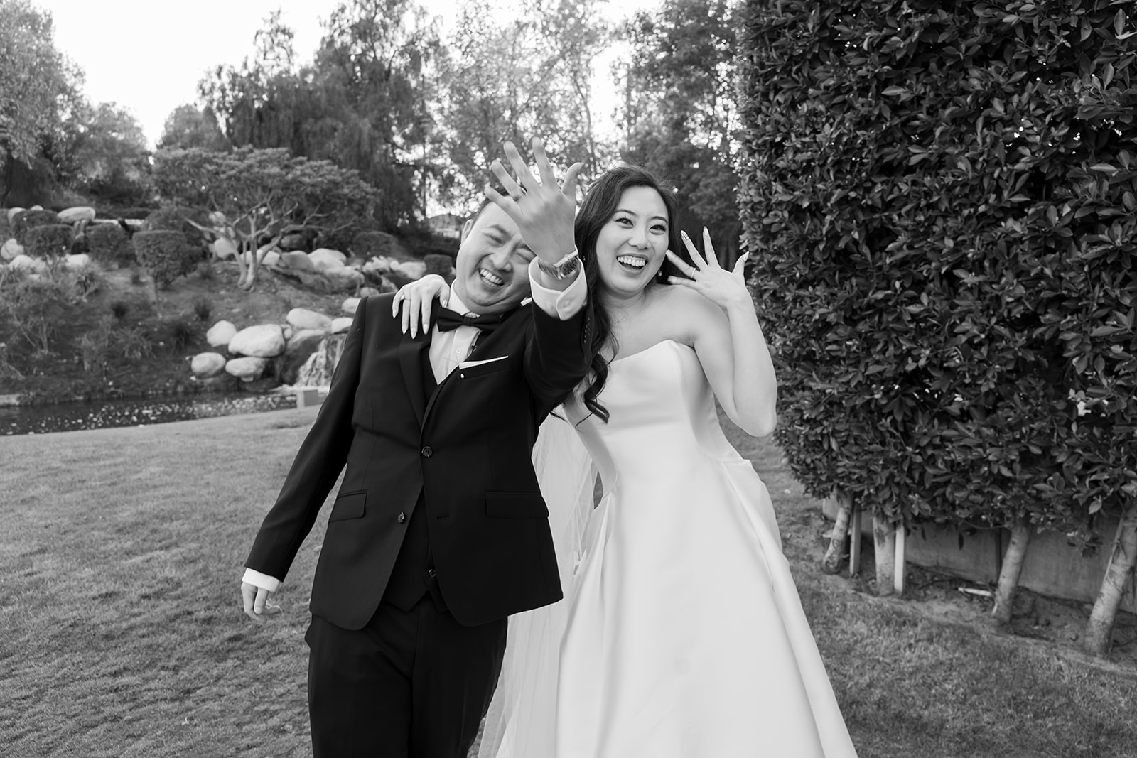Black and white photo of a bride and groom holding up their hands in celebration after the ceremony.