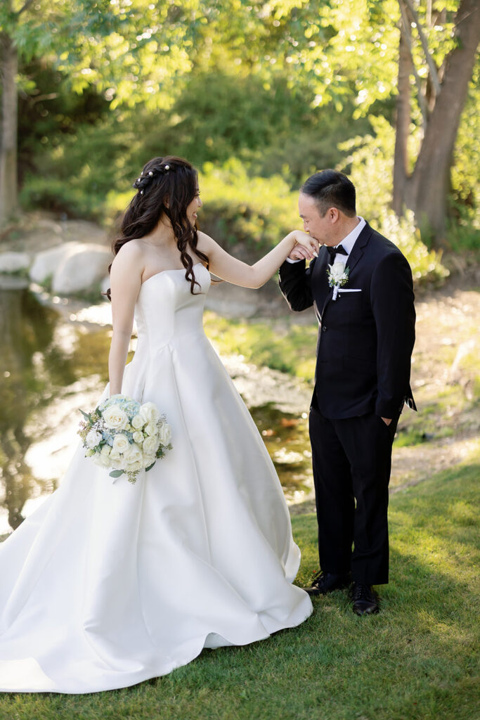 Groom kissing the brides hand after sharing a first look.