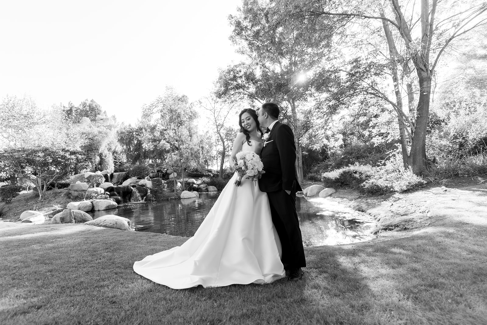 Black and white portrait of a bride and groom posing in front of a pond at Coyote Hills Golf Course.