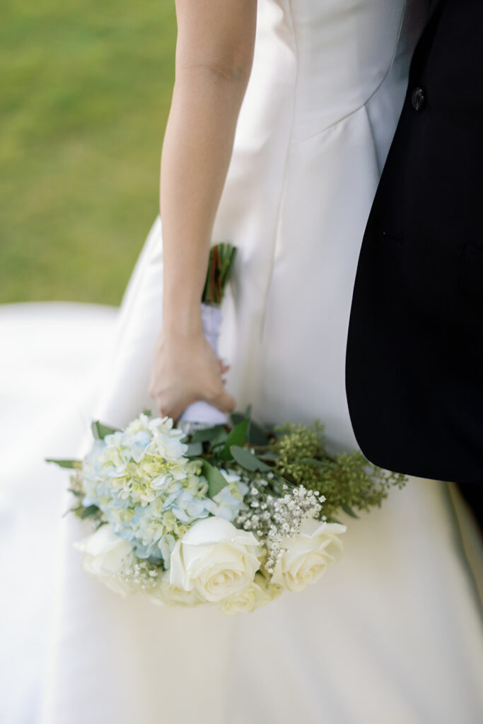 Close up shot of a bride holding her blue and white wedding bouquet.