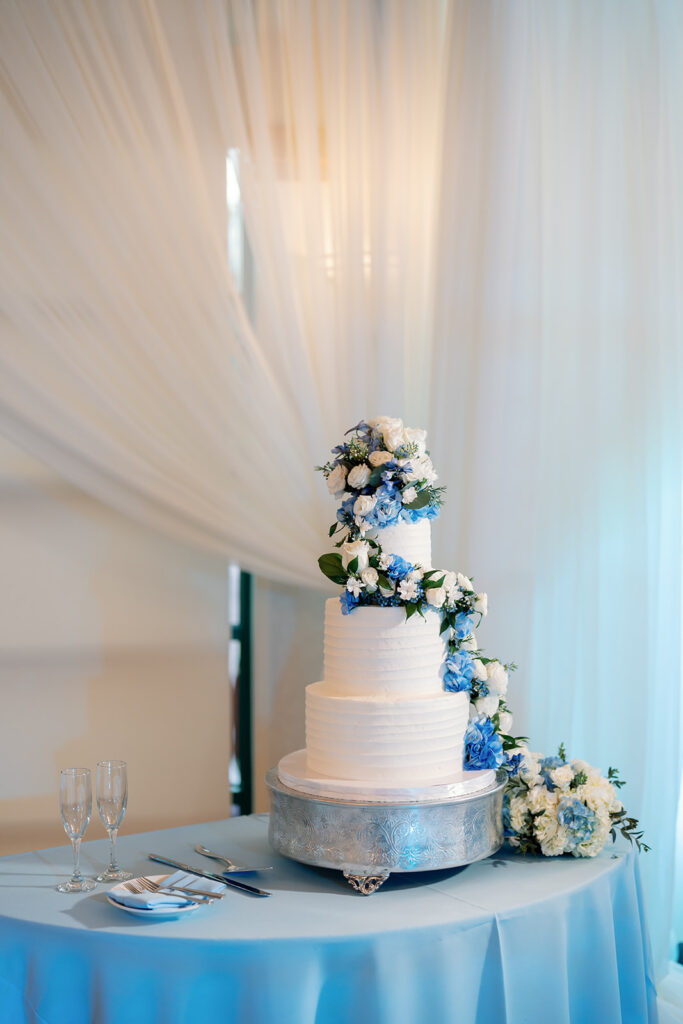 Four tiered white wedding cake with cascading florals.