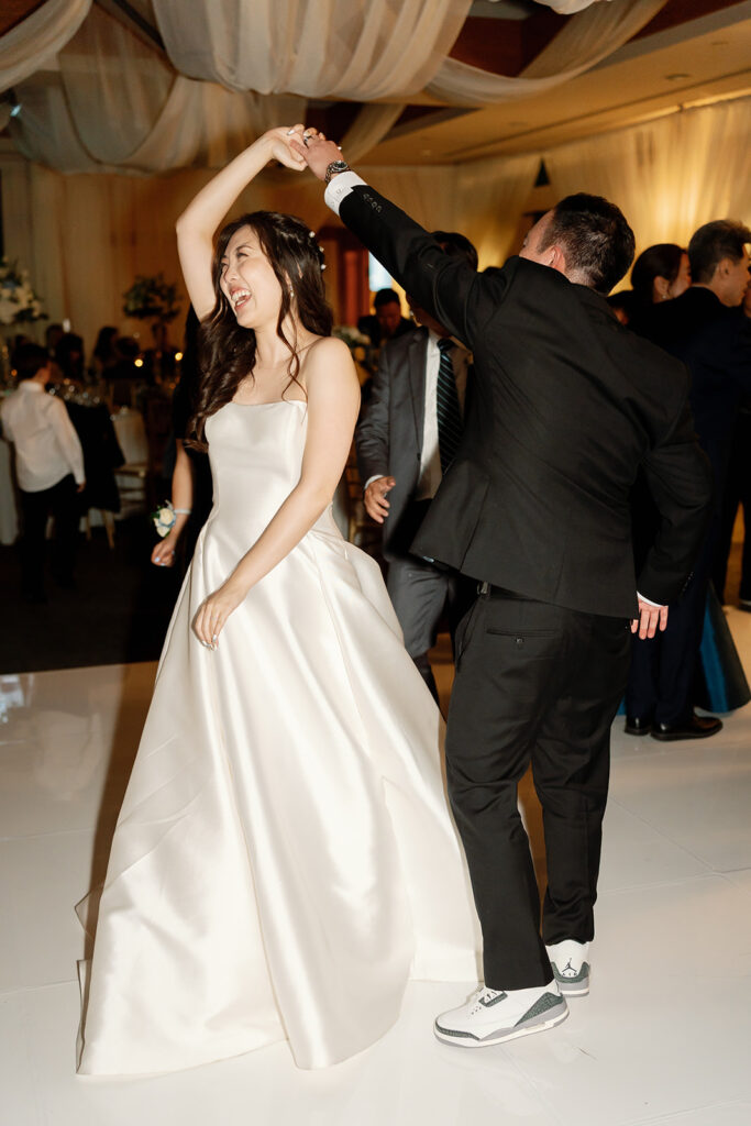 Groom twirling his bride as they dance during the reception. 
