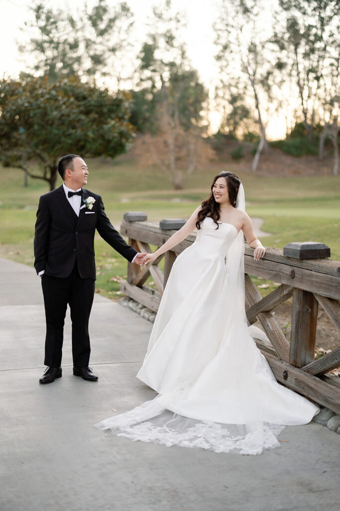 Bride and groom holding hands on a bridge at Coyote Hills Golf Course.