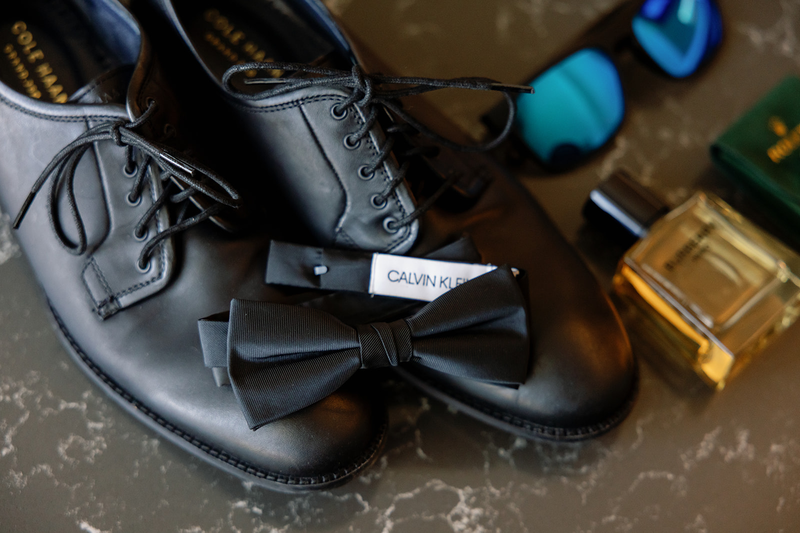 Grooms wedding details with shoes, cologne, and sunglasses. 