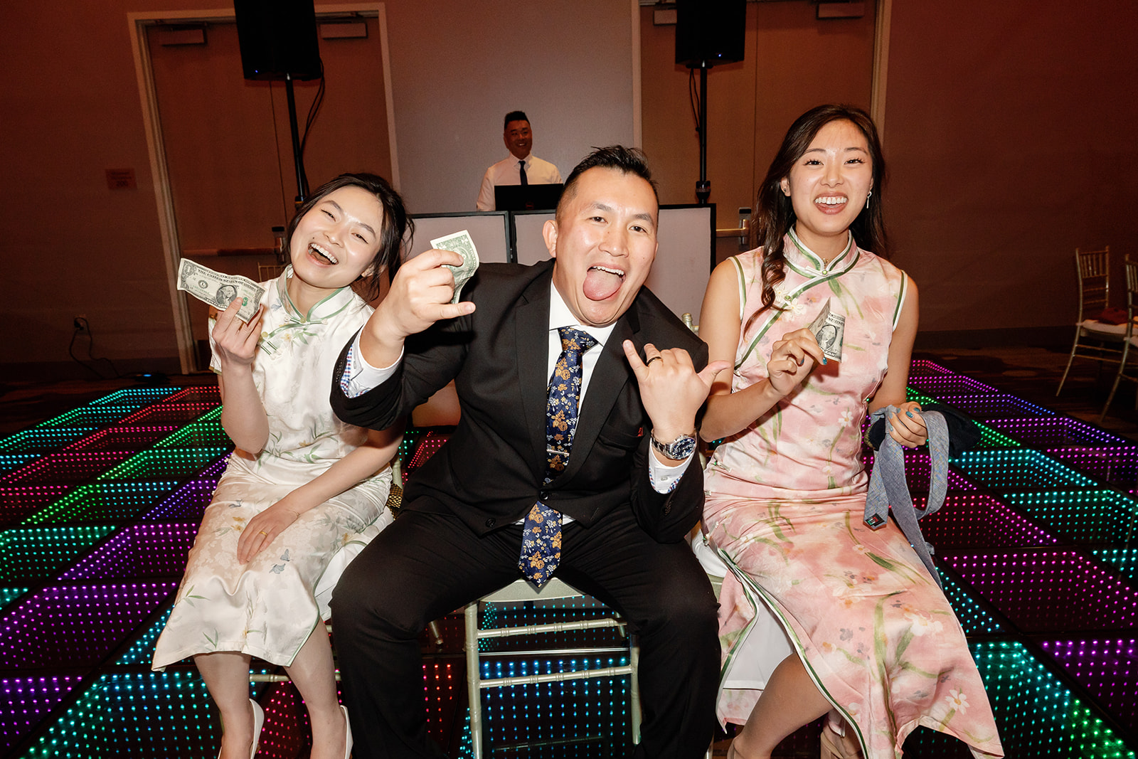 Wedding guests seated with dollar bills and smiling while playing tea ceremony games.