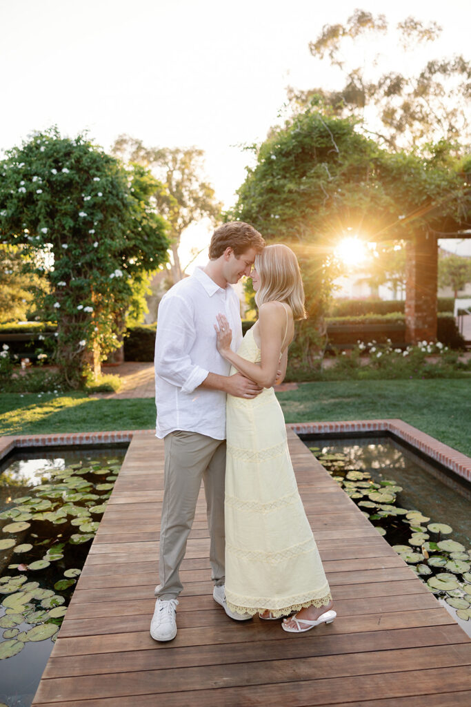 Couple posing on the walking path next to the arbor and lily pond after their Santa Barbara proposal at El Encanto.