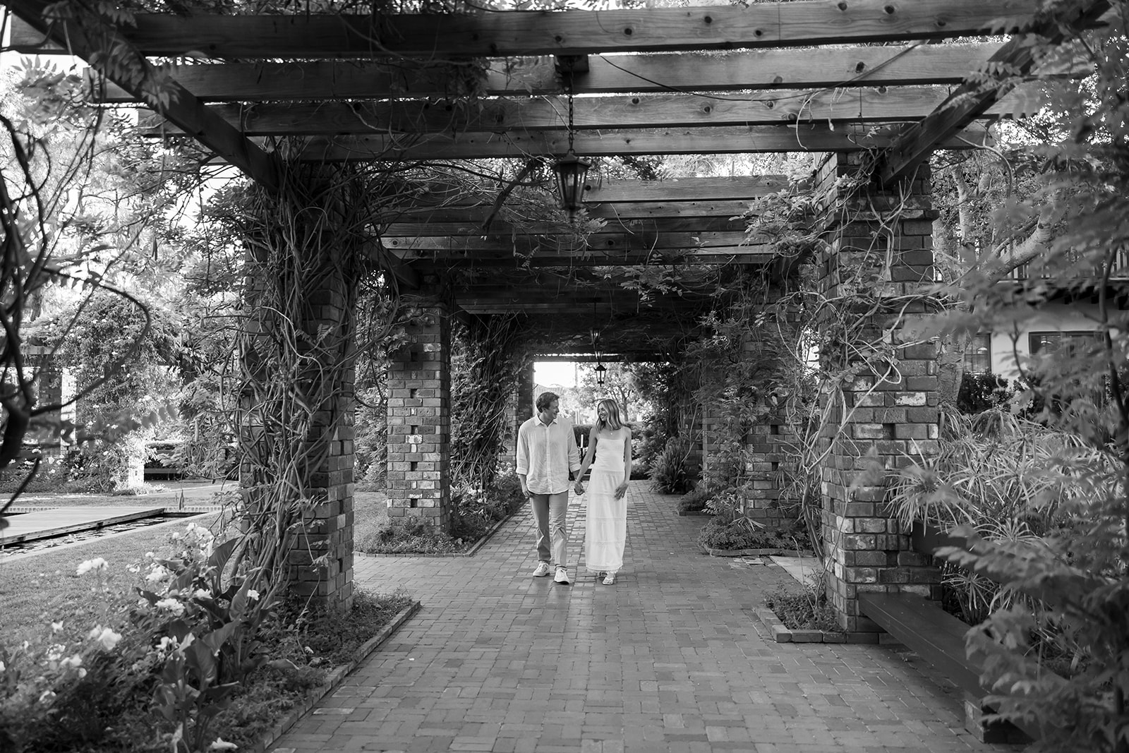 Black and white photo of a couple walking under the arbor together at El Encanto after their Santa Barbara surprise proposal.