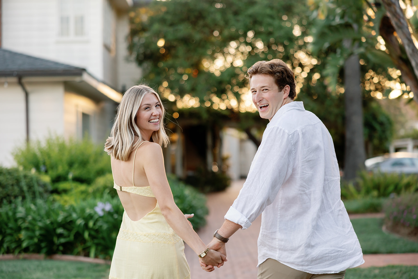 Newly engaged couple laughing together on a garden pathway at El Encanto.