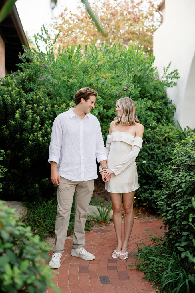Newly engaged couple posing together on a garden pathway at El Encanto.