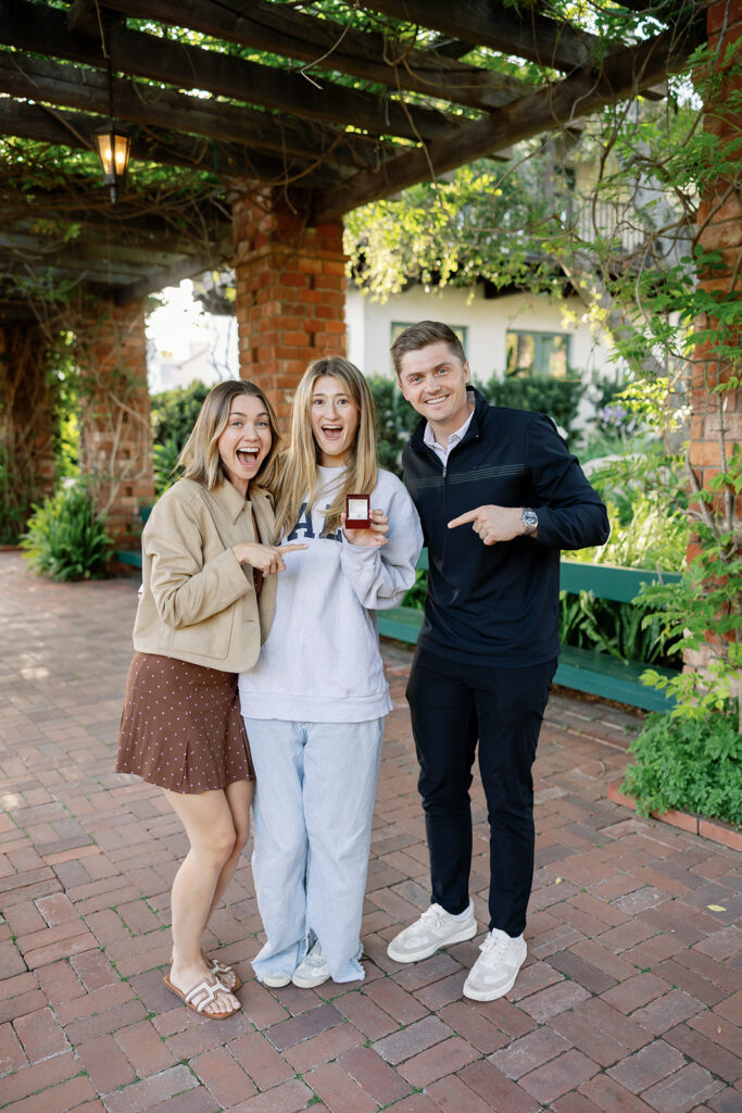 Siblings posing with the engagement ring.