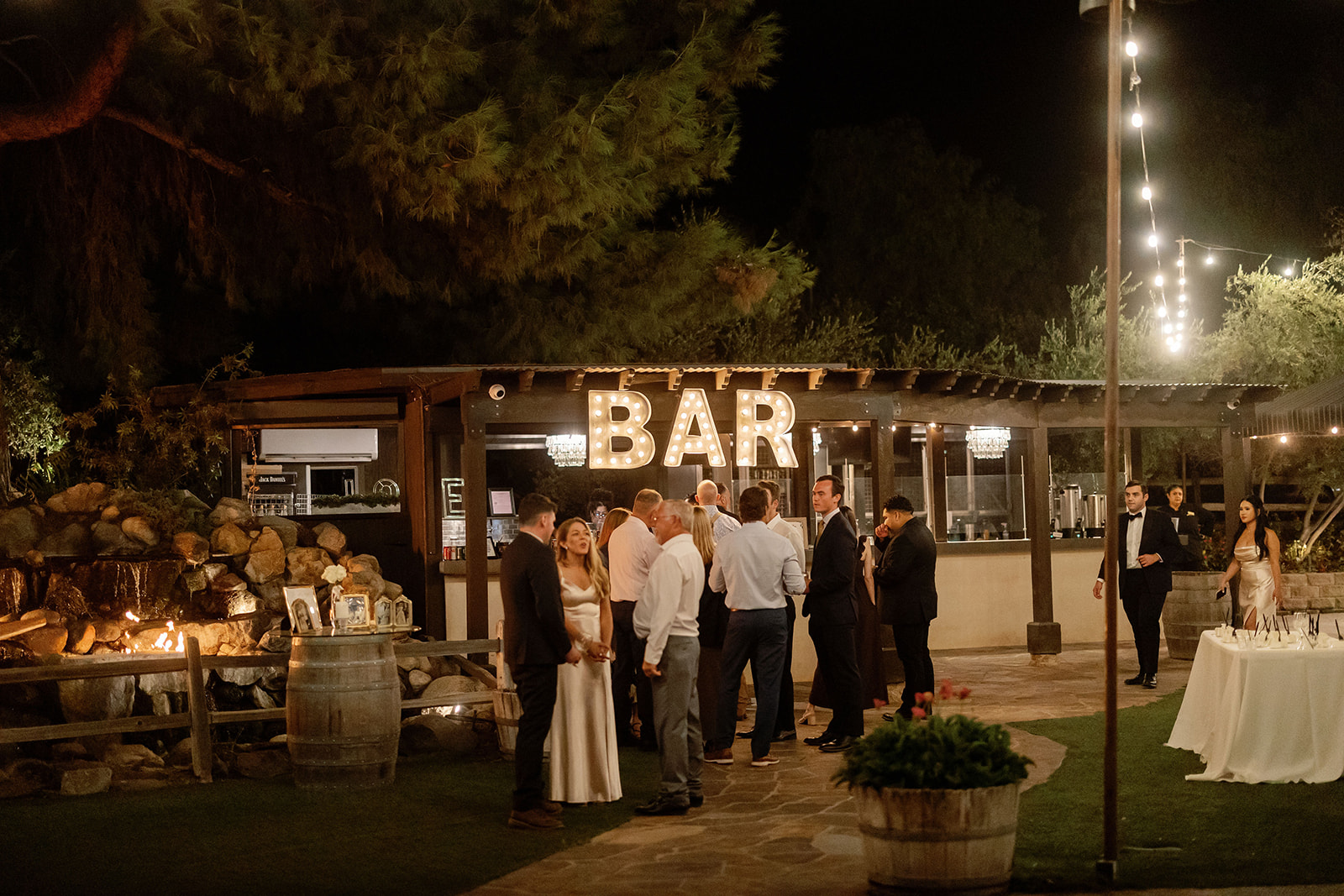 Guests gathered near the outdoor bar and fire feature during a Lake Oak Meadows wedding reception.