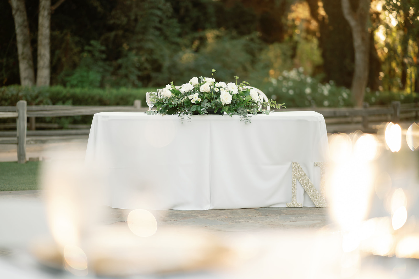 Outdoor sweetheart table with white florals and candles.