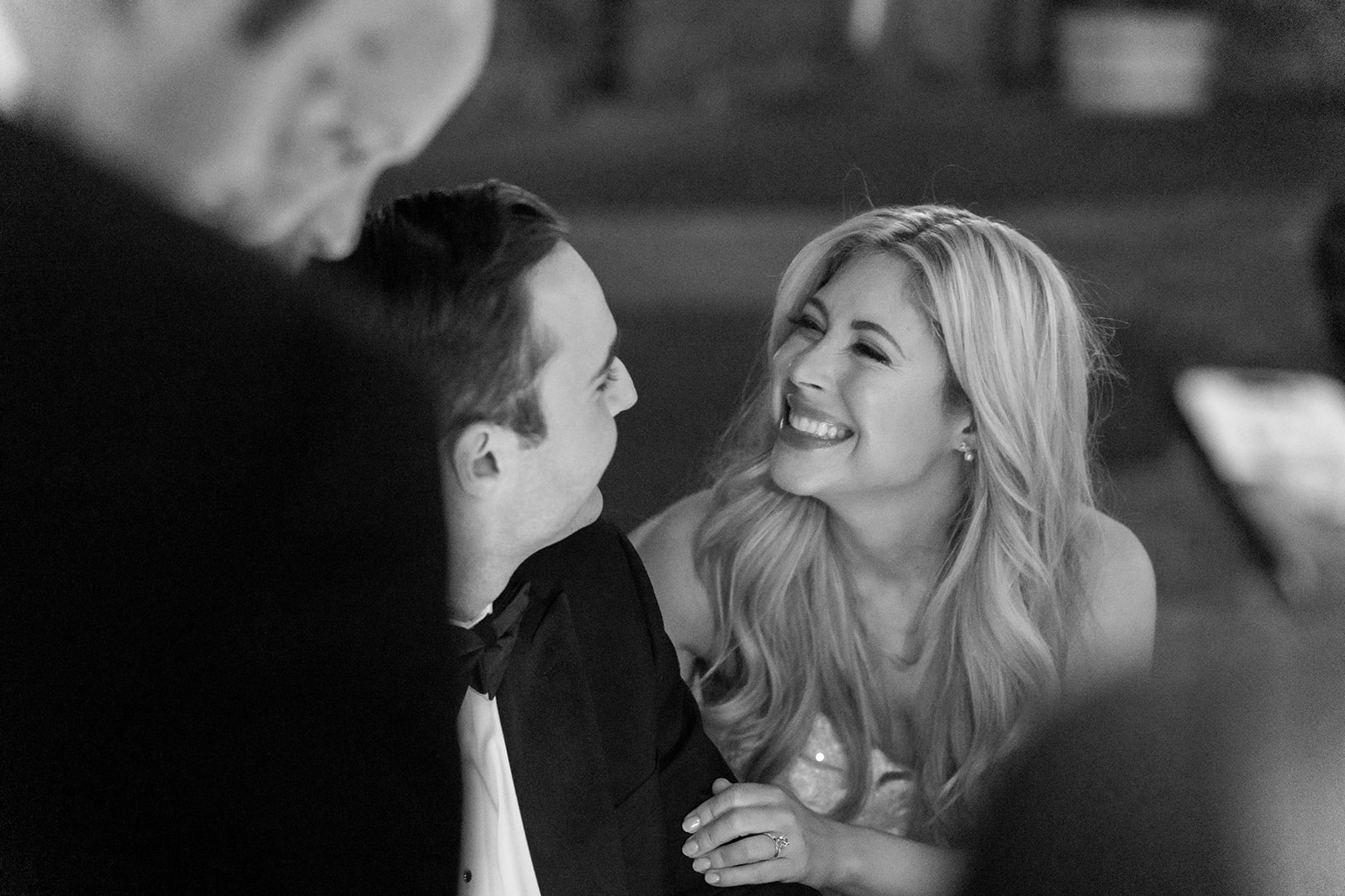 Black and white photo of a bride and groom smiling during their reception.