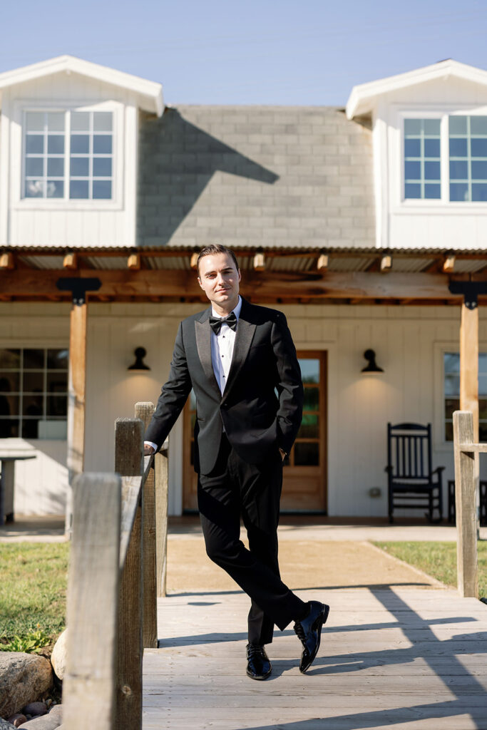 Groom standing on the dock outside the getting ready house before a Lake Oak Meadows wedding.