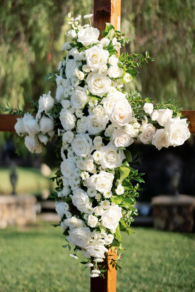 White floral cross for an outdoor wedding ceremony.