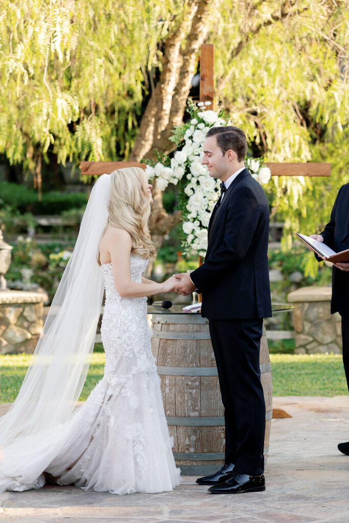 Bride and groom holding hands during their outdoor Lake Oak Meadows wedding ceremony.