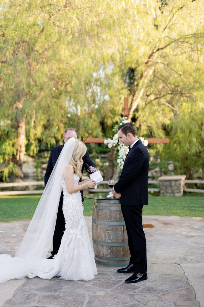Bride reading vows to groom during an outdoor wedding ceremony at Lake Oak Meadows.