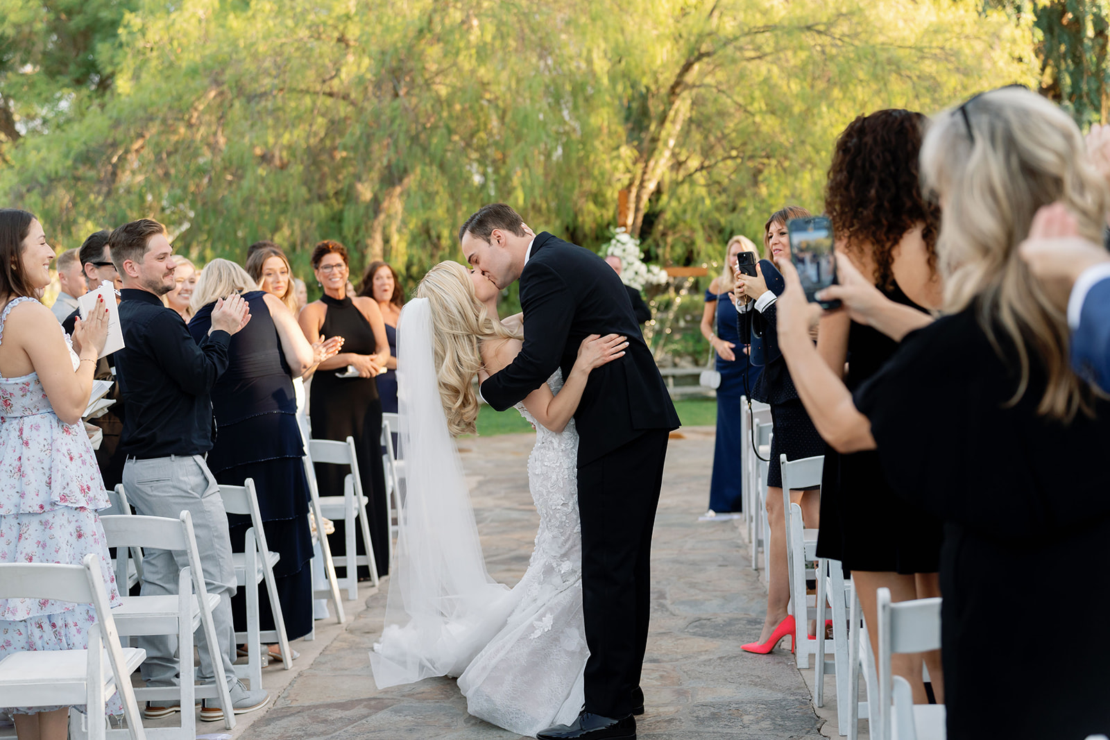 Bride and groom sharing an end of the aisle kiss after their Lake Oak Meadows wedding ceremony outdoors.