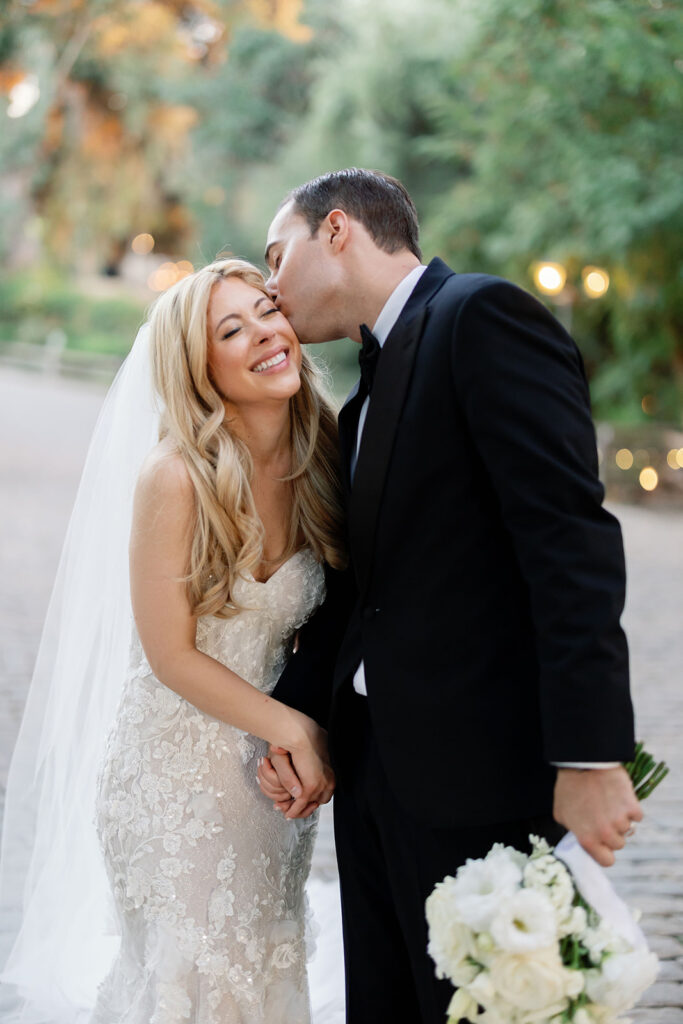Groom kissing the bride on the cheek during their outdoor portraits.