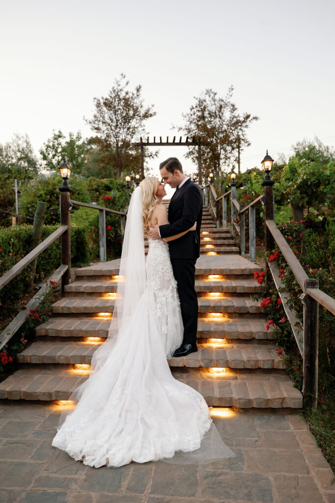 Bride and groom posing on a staircase at Lake Oak Meadows in Temecula during dusk.