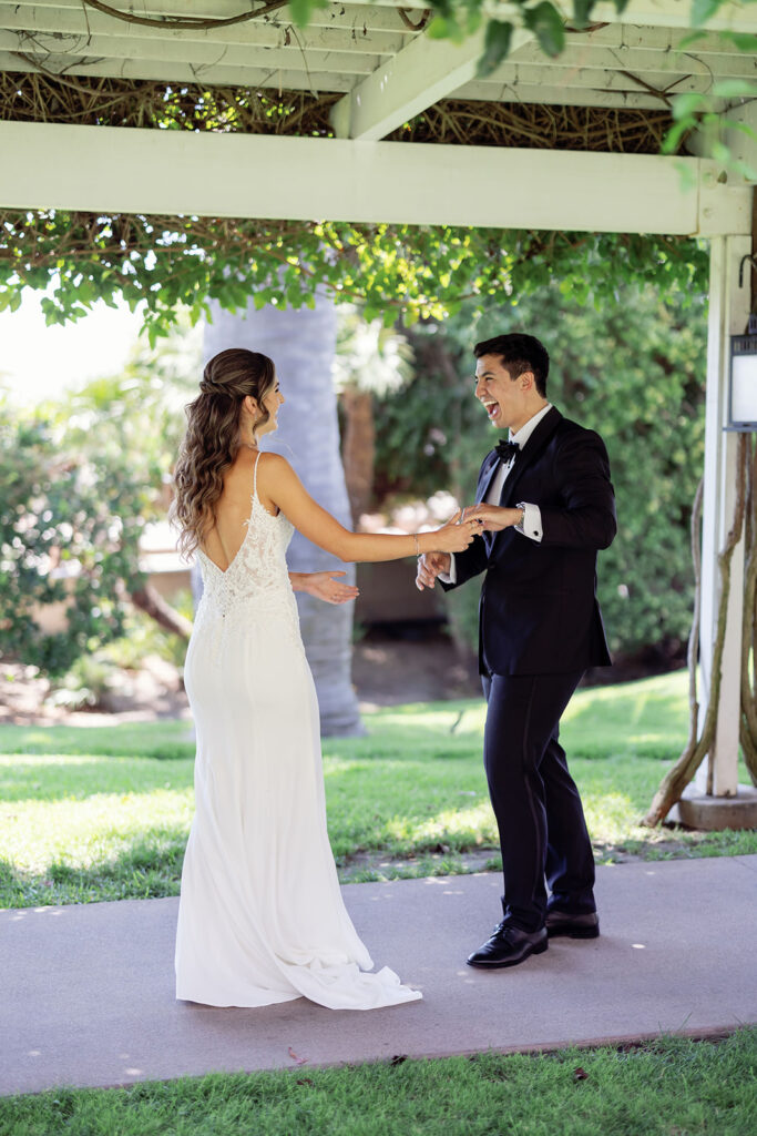 Couple smiling during their first look beneath a vine-covered pergola at Hyatt Regency Newport Beach.