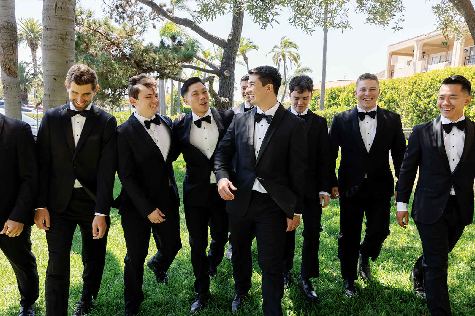 Outdoor candid photo of a groom and groomsmen taking photos outdoors. 