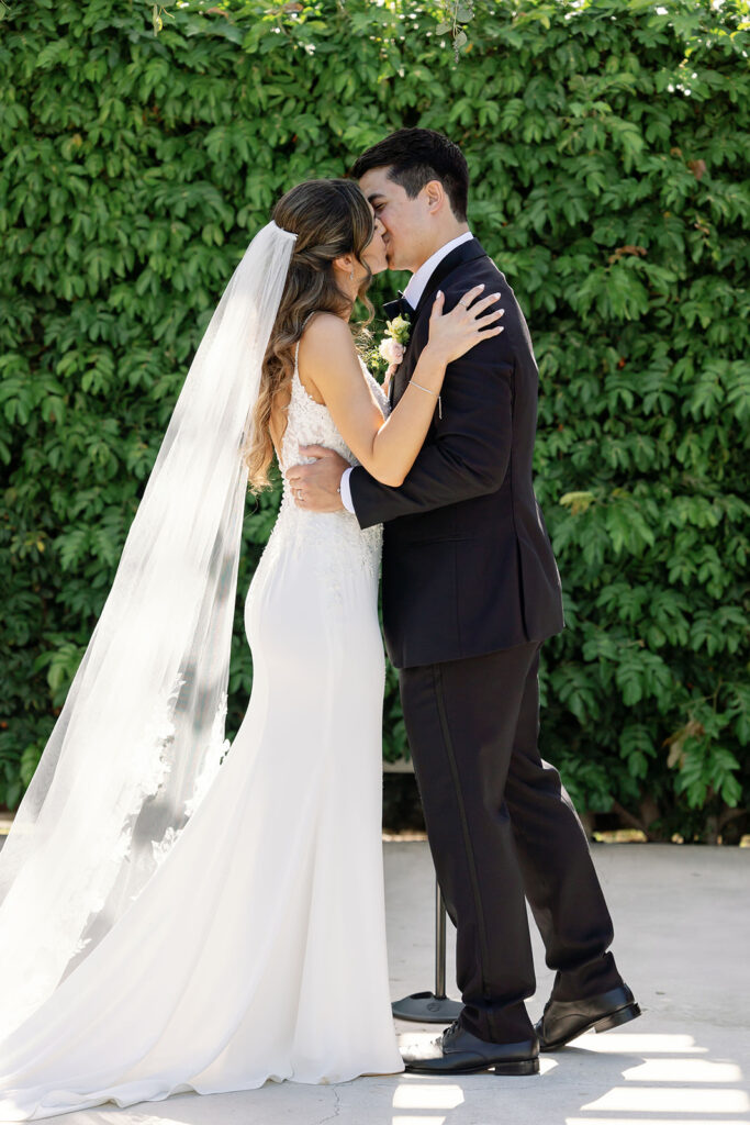 Couple sharing their first kiss during an outdoor Hyatt Regency Newport Beach wedding ceremony.